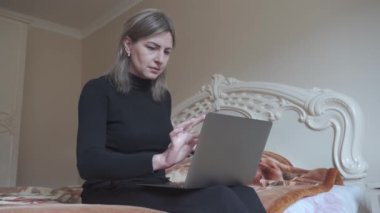 Dizüstü bilgisayarında yazı yazan ve kucağında tutan bir kadının elleri. Bilgisayarda metin mesajları kullanmak.