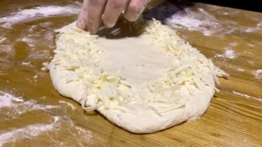 Ev yapımı pişirme için hamur hazırlığı. Erkeklerin elleri ahşap bir masanın üzerindeki hamurla çalışır. Tarifi takip ederek ev yapımı ekmek hazırlıyorum..