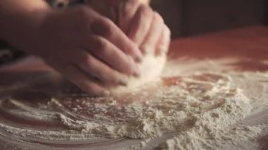Sabahın erken saatlerinde, dişi eller hamuru ahşap bir masada yoğurur. Evde ekmek yapıyorum. Yan görünüm.