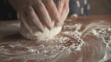 Sabahın erken saatlerinde, dişi eller hamuru ahşap bir masada yoğurur. Evde ekmek yapıyorum. Yan görünüm.