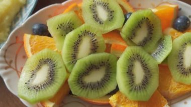 Meyve dilimleri, kivi, portakal ve böğürtlen bir tabakta güzelce sıralanmış. Bol vitaminli sağlıklı yiyecekler. C vitamini.