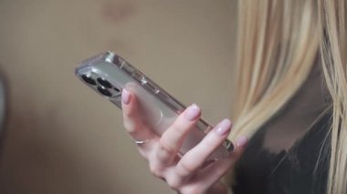 Genç bir kız elinde bir telefon tutuyor ve internette sitelere bakıyor. Online mağazadan mal seçiyor ve evde alışveriş yapıyor..