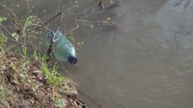Plastik bir şişe nehirde yüzüyor. Su kaynaklarının plastik atıkla kirlenmesi. Ekolojik sorunlar.