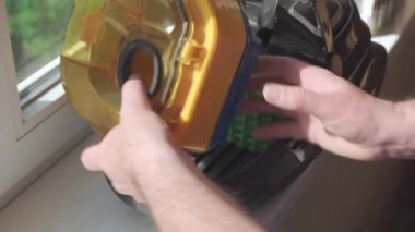 Male hands take the filter out of the vacuum cleaner and check its condition. Close-up shot