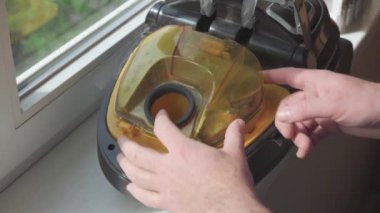 Male hands take the filter out of the vacuum cleaner and check its condition. Close-up shot