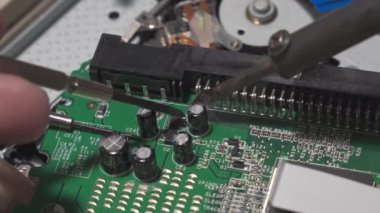 Repair of digital electronic board. The repair engineer works with a soldering iron. Close-up, shallow depth of field.