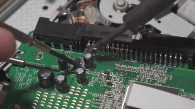 Repair of digital electronic board. The repair engineer works with a soldering iron. Close-up, shallow depth of field.
