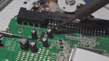 Repair of digital electronic board. The repair engineer works with a soldering iron. Close-up, shallow depth of field.
