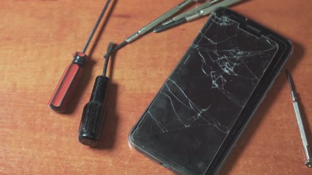 Ein Kaputtes Smartphone Mit Zerbrochenem Schutzglas Liegt Auf Dem Schreibtisch — Stockvideo