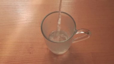 Pour hot water into a glass cup for brewing tea. Dip the tea bag into boiling water. View from above