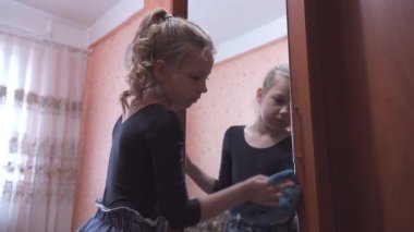 Okul çağındaki bir kız dairesini temizliyor. Dolap aynasını özenle siler, ailesinin evi temizlemesine yardım eder..