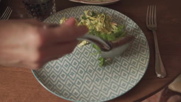 皿はテーブルの上に立ち 女性の手の中に野菜サラダのスプーンを置きます 健康食品の摂取量 おやつの時間 — ストック動画