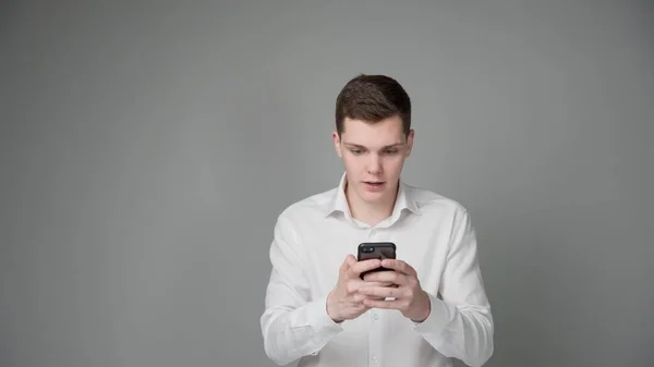 Jeune Homme Surpris Regarde Écran Son Smartphone Sur Fond Gris — Photo