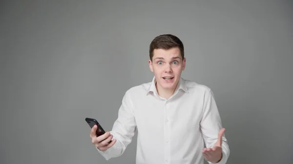 Surprised Young Guy Looks Screen His Smartphone Gray Background High — Stock Photo, Image