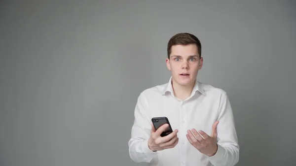 Jeune Homme Surpris Regarde Écran Son Smartphone Sur Fond Gris Images De Stock Libres De Droits