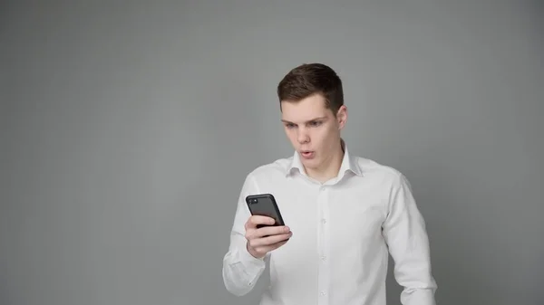 Jeune Homme Surpris Regarde Écran Son Smartphone Sur Fond Gris Images De Stock Libres De Droits