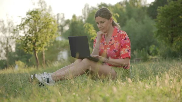 Задумчивая Молодая Женщина Сидит Траве Парке Пользуется Ноутбуком Электронное Обучение — стоковое фото