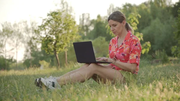 Женщина Средних Лет Сосредоточена Работе Ноутбуком Сидит Парке Вдали — стоковое фото