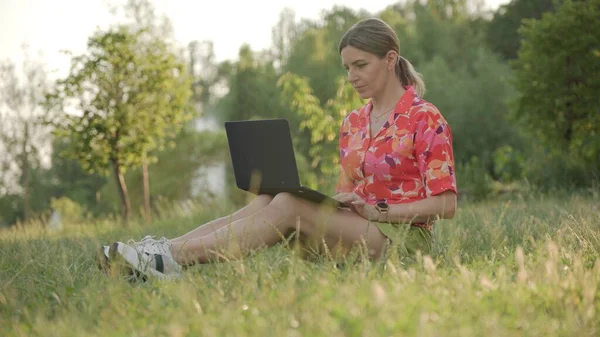 Молодая Женщина Использует Ноутбук Сидя Траве Парке Пристально Смотрит Экран — стоковое фото