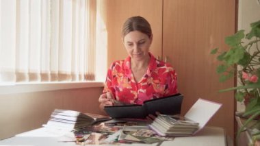 Kadın tarihçi, orta yaşlı, arşiv fotoğraflarını dikkatlice inceleyen, tarihi gerçekleri eşeleyen. 4k video.