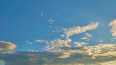 Gün batımında güneşle aydınlanan yüzen bulutlu mavi gökyüzü. Zaman aşımı.