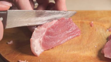 Kadının eli kesme tahtasında bıçakla et kesiyor. Yakın plan..