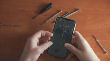 Ustanın elinde kırık camlı telefon. Ekipman onarımı.