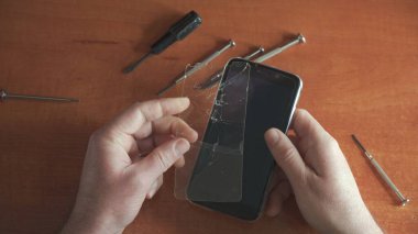 Ustanın elinde kırık camlı telefon. Ekipman onarımı.
