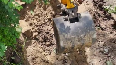Excavator bucket when excavating soil. Work of construction equipment on construction site.