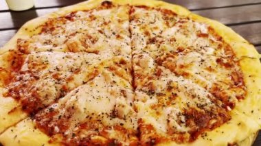 Peynirli taze, kokulu pizza, parçalara ayrılmış, yemek masasında yatıyor..