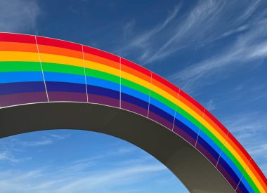 Çok renkli gökkuşağının kavisi bulutlu mavi gökyüzünün arka planına karşı...