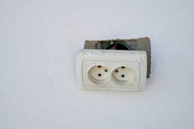 Kırık elektrik prizi beyaz bir duvarda..