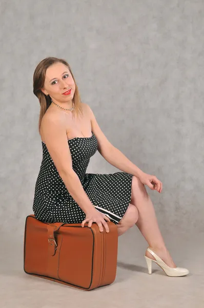 Girl sitting on brown retro suitcase — Stock Photo, Image