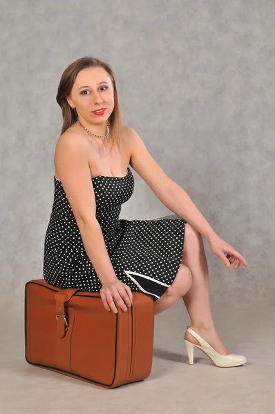 Girl sitting on brown retro suitcase — Stock Photo, Image