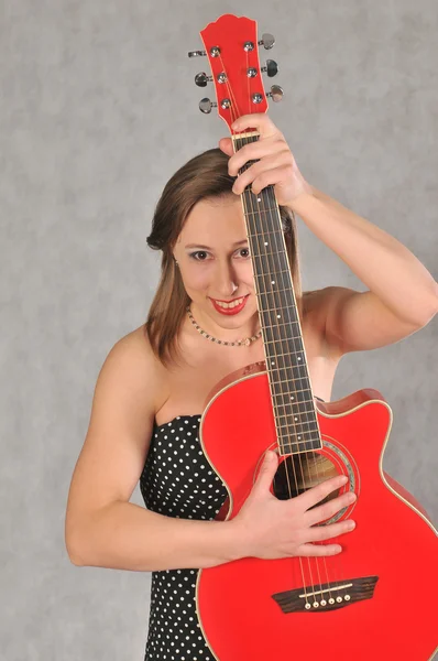 灰色の背景の赤いギターを持つ感情的な少女 — ストック写真