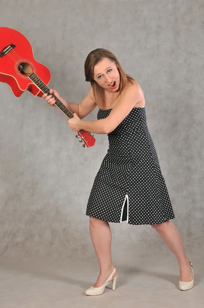 Glad tjej vifta med en röd gitarr — Stockfoto