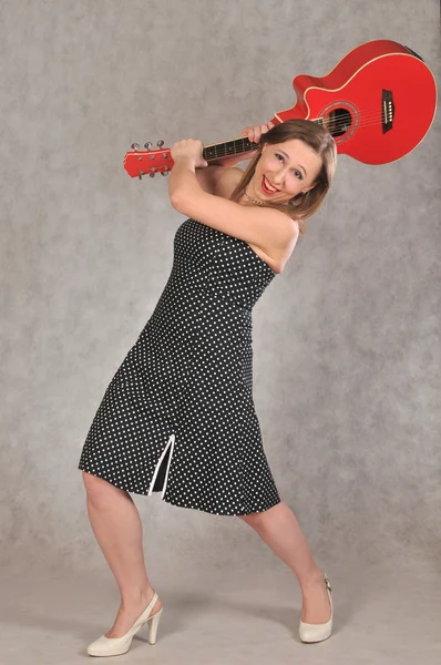 Iloinen tyttö heiluttaa punaista kitaraa — kuvapankkivalokuva