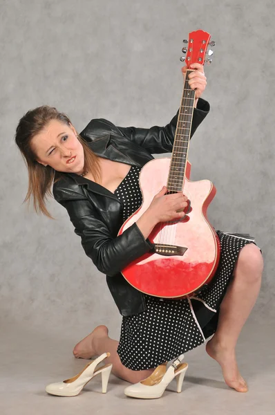 Menina emocional com uma guitarra vermelha, em um fundo cinza — Fotografia de Stock