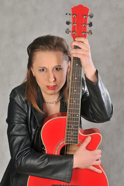 Fille émotionnelle avec une guitare rouge, sur un fond gris — Photo