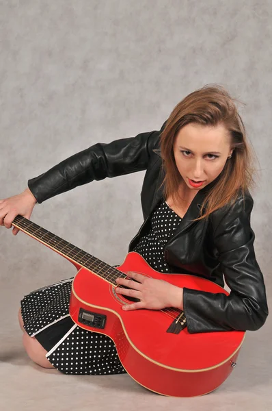 Gri arka plan üzerinde kırmızı bir gitar ile duygusal kız — Stok fotoğraf