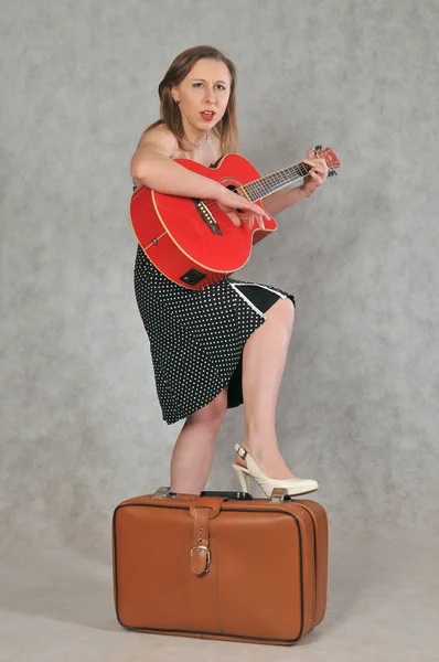 Веселая девушка с красной гитарой и ретро-чемоданом — Stock fotografie