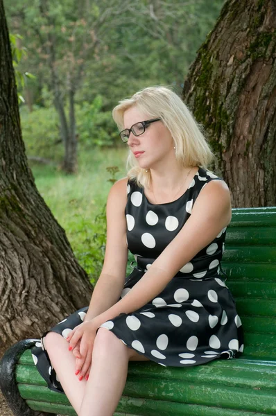 Menina bonita sentada em um banco de parque — Fotografia de Stock