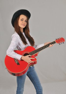 Siyah şapkalı kız beyaz gömlek, kot pantolon ve kırmızı gitar elinde tutan kovboy kemer