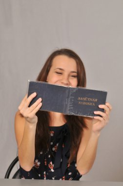 koyu kahverengi kız masada ve kahkaha ile otururken karanlık vintage elbise çiçek gradebook görünüyor