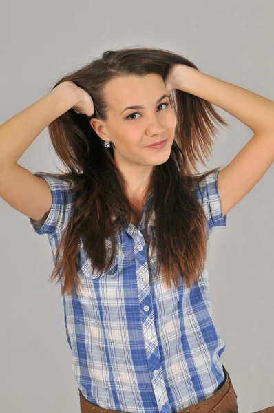 Porträt einer jungen dunkelhaarigen, lächelnden zwanzig Mädchen mit Händen, die ihr Haar heben — Stockfoto