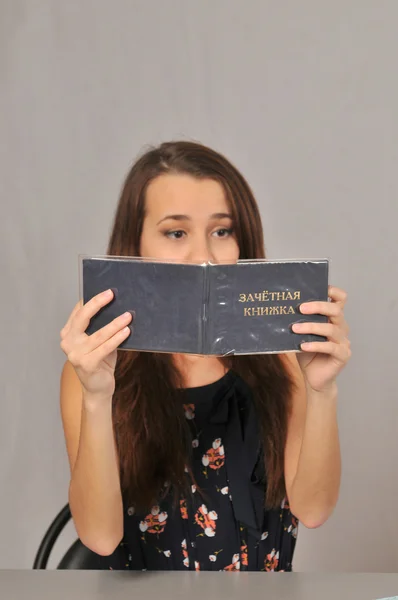 A girl is sitting at the Desk and looks at gradebook — Stock Photo, Image