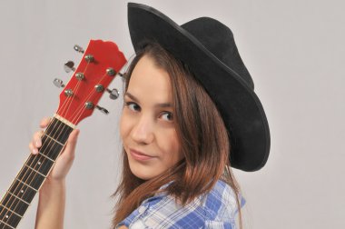 Kırmızı boyun bir gitar bir kişiden tutan genç bir yirmi yaşındaki kızın siyah şapkalı, portre.