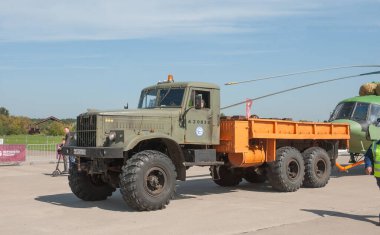 Zhukovsky, RUSSIA - 29 Ağustos 2019: KrAZ-255B yük kamyonu traktörü, Mil Mi-17V5 Hip helikopterini dijital kamuflajla MAKS-2019 hava gösterisini kamufle etmek üzere Rus askeri nakliye aracını çekti