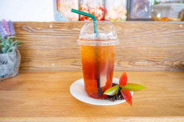 Paket plastik bardakta soğuk buzlu çay, yeşil pipet ve güzel dekore edilmiş bir kafe.