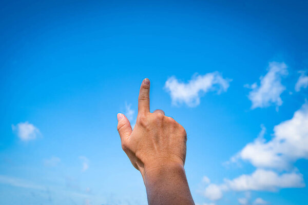 Man hand pointing at something or touching screen on blue sky with cloud background, closeup of hand